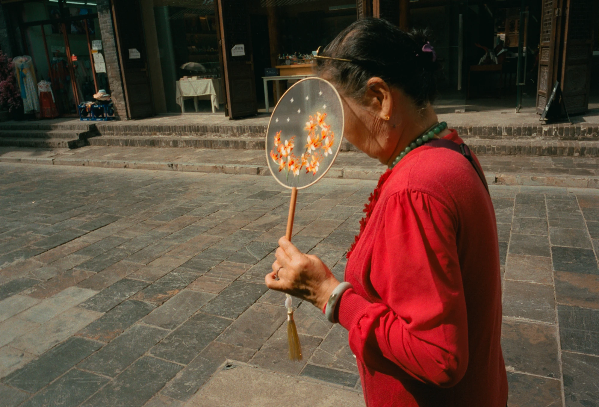 Una donna con un ventaglio nel cortile di un tempio in Cina.